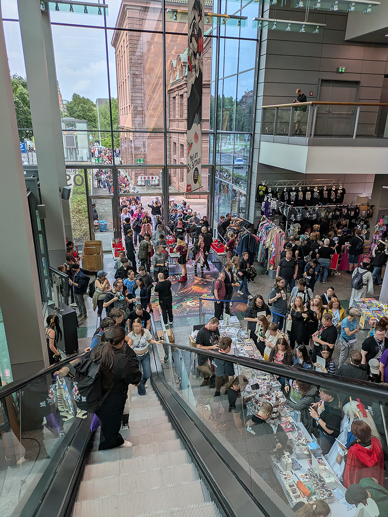 photo taken inside the convention hall. Through the class you cann see guests wating in line outside to get in in.